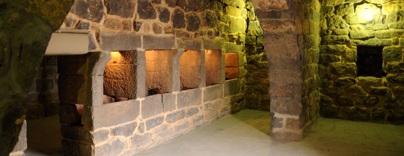 Main image: An interior view of the proposed site museum's planned library and gift shop. Being restored from an early Islamic home, ancient mangers are visible along with a 20th century Druze arch in the foreground. Restored sections of the room can be discerned from the lighter mortar in use.